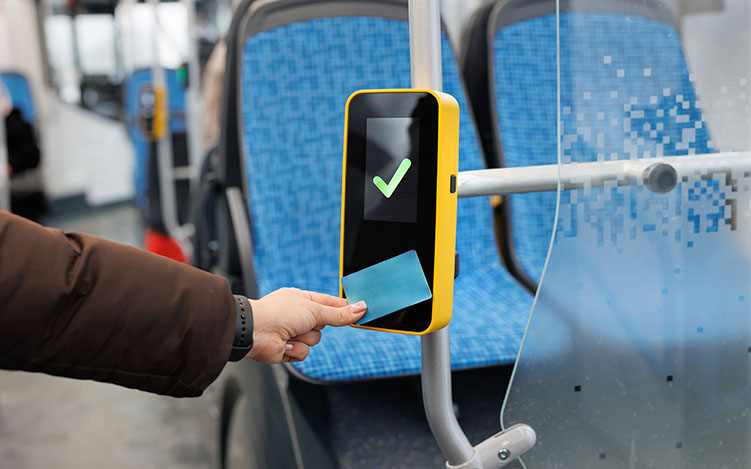 Photo of hand holding a card to a card reader on a bus